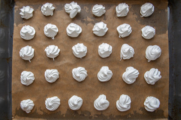 Top view of white raw meringues on brown paper