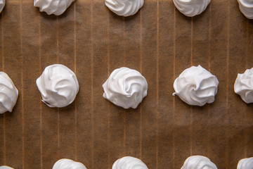 Top view of white raw meringues on brown paper