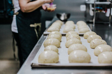 Obraz premium Bakery concept. Working woman preparing the dough before putting them to bake. Lifestyle.
