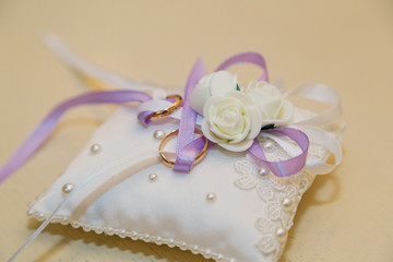 two gold rings on a white pillow pad. The concept of unity and wedding celebration.