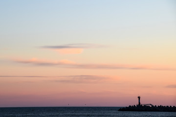 Naklejka na ściany i meble lighthouse silhouette and setting sun sunset red sky clouds