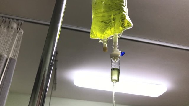 Yellow bag of intravenous chelation therapy dripping slowly in a hospital room. Close up