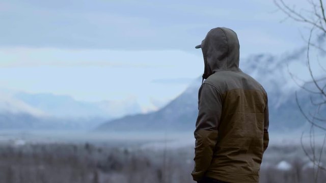 Man in jacket looking into distance, pan revealing Alaskan landscape 4k