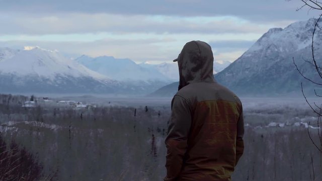 Slow pan around man looking over winter landscape of Anchorage Alaska 4k