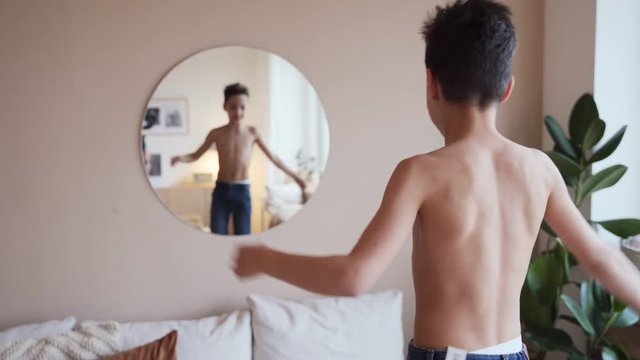 Confident kid looking at his muscles in mirror imagining that he is super hero