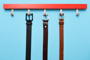 Male leather belt on hanger on colored background.
