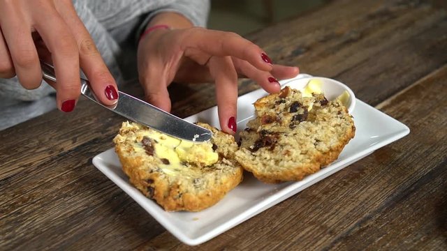 SLOWMO - Young woman Spreading butter on traditional homemade New Zealand scone at stylish cafe