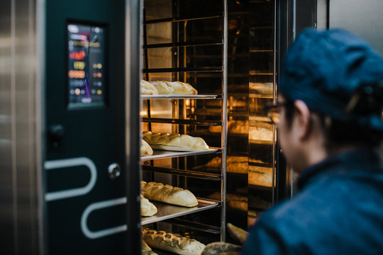 .Working woman using the bakery oven to bake the bread of the day. Bakery concept. Lifestyle..