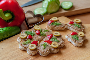 heart shaped canape with liver pate, decorated with olives, sweet peppers and dill, cooking at home, close up