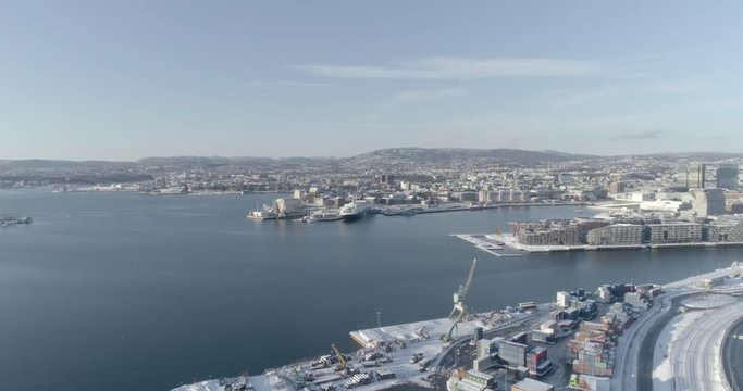 4K high angle aerial view of the beautiful Oslo skyline with the brand new Bj&oslash;rvika Opera quarter and the hills in Holmenkollen in the distant background, in vibrant winter sunlight.