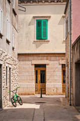 Fototapeta na wymiar Street with green bicycle and window shutters, Vela Luka, island of Korcula, Croatia