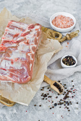Raw pork ribs on a wooden chopping Board. Gray background, side view, space for text