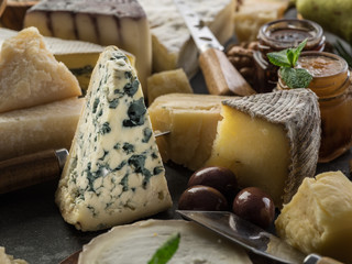 Assortment of different cheeses with olives and jams. Food background.