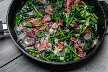 Peas sprouts, young spinach leaves fried in a pan together with a crispy, bacon-flavored