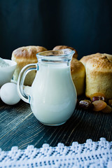 Carafe with milk in the background Easter cakes on a dark background. Fresh cakes with dried fruits. The process of cooking Easter cake. View from the side.