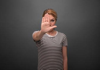 Woman pulls her hand palm forward. Stop sign. On a gray background.