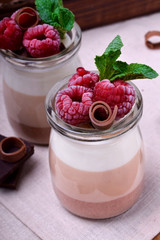 Three chocolate mousse dessert in a glass jar garnished with frozen raspberries
