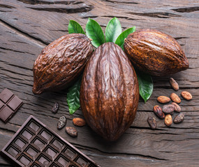 Cocoa pod, cocoa beans and chocolate on the wooden table. Top view.