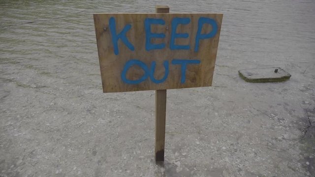 Wooden keep out sign on a lake