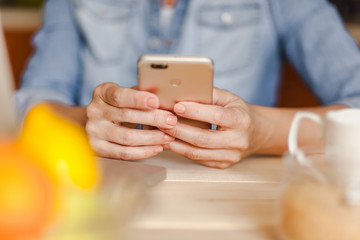 Mid adult woman using smart phone in kitchen. Close up