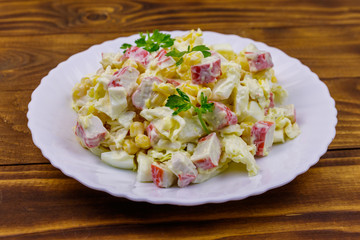 Salad with crab sticks, sweet corn, chinese cabbage, eggs and mayonnaise on wooden table
