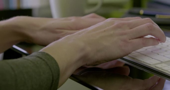 Pan left of female hands typing on keyboard