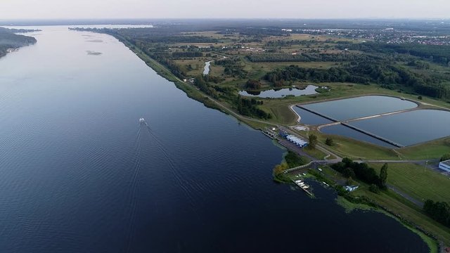 Serene calm lake waters of Serock town countryside, on the lush green shoreline with a boat cruising by