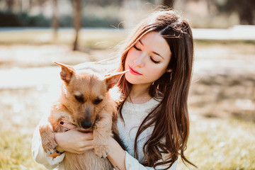 .Beautiful young woman playing outdoors with her little brown adopted dog. Hugs and kisses....