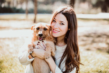 .Beautiful young woman playing outdoors with her little brown adopted dog. Hugs and kisses. Dogfriendly concept. Lifestyle.