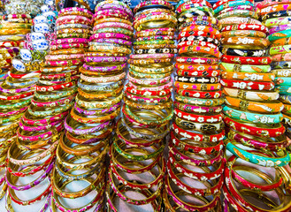 Fototapeta na wymiar A stack of multi colored shiny metal bracelets on a table in a tourist market place gift shop store. Hong Kong.