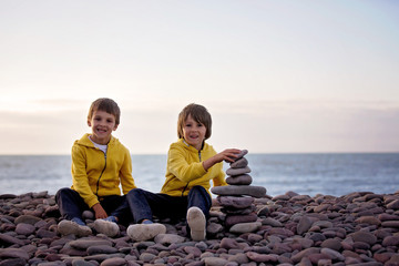 Children, playing on a rocky beach, throwing stones