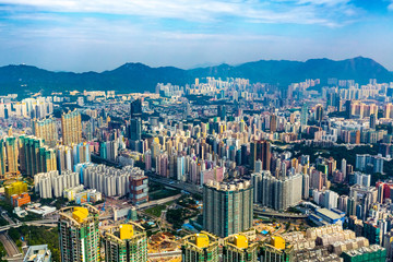 A high set skyscraper aerial view of Hong Kong city skyline and high density apartment blocks with distant mountains. Copy space.