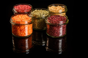 five small glass jars filled with different colors sea salt