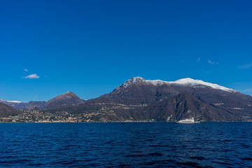 Italy, Bellagio, boat on Lake Como with snow mountain behind