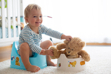 Cute toddler boy, potty training, playing with his teddy bear