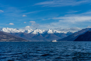 Fototapeta na wymiar Italy, Bellagio, boat on Lake Como with snow covered peaks background