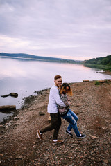 Young couple having fun and running along the river