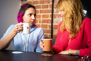 two young women with the cups of tea and coffee talking