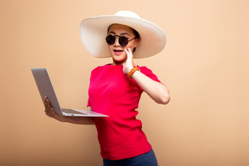 Woman wearing hat and sunglasses use laptop isolated on background