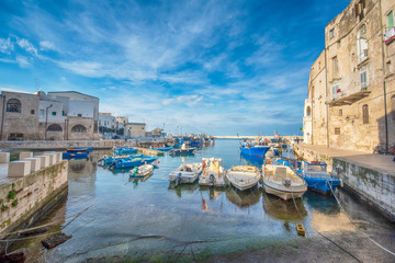Old port of Monopoli province of Bari, region of Apulia (Puglia), southern Italy. Boats in the marina of Monopoli. Fortified wall and rocky beach with a clear blue water. 