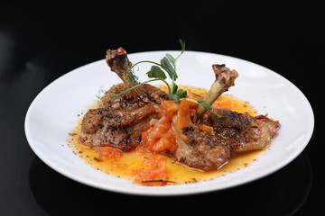 fried chicken leg with tomatoes and spices on a plate