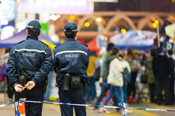 Two police watch people at a crowd control cordon line. Hong Kong.