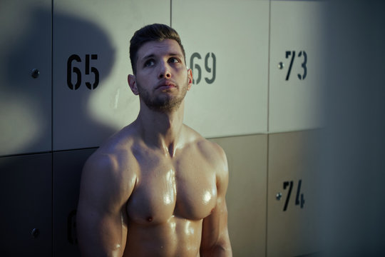 Sweaty Pensive Athletic Man Sitting In Gym's Dressing Room.