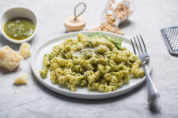 Plate of pasta fusilli with pesto sauce on gray concrete background