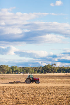 A Farmer In A Red Tractor Plowing Land Using A Drag Chain Harrow.  Victoria, Australia.