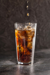 Glass of coke with ice on a dark background. Carbonated beverages. Selective fokus.