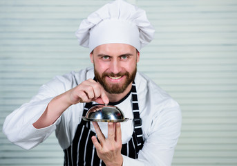 Haute cuisine is not snooty. Chef cook in uniform standing with delicious dish. Handsome man in...