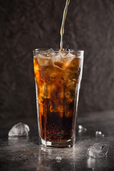 Glass of coke with ice on a dark background. Carbonated beverages. Selective fokus.
