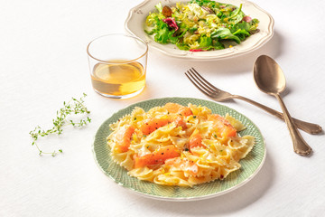 Pasta and wine, Italian dinner. Farfalle with smoked salmon and cream sauce, with a glass of wine, mesclun leaves salad, and a place for text