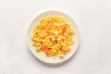 Smoked salmon with bowtie pasta. Farfalle with salmon and a cream sauce, shot from the top on a white linen tablecloth with a place for text